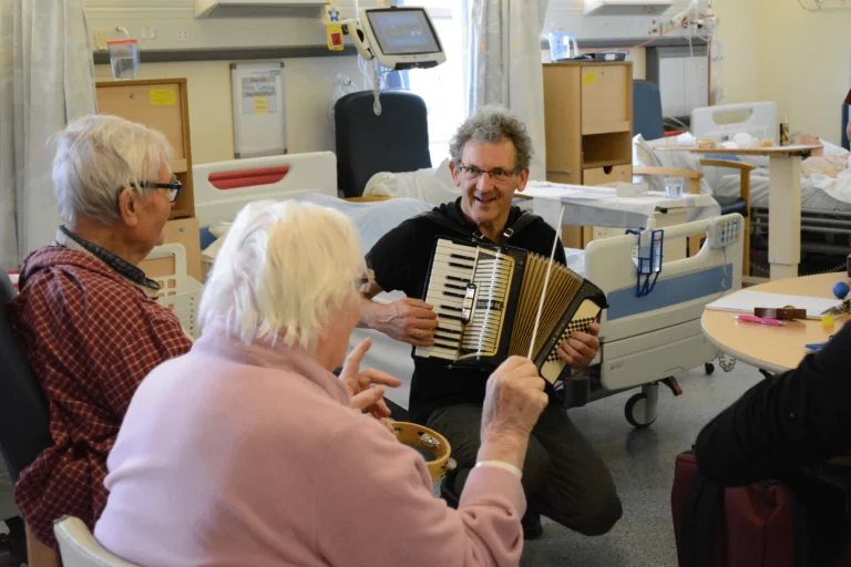 hugh playing accordion to the elderly in a hospital